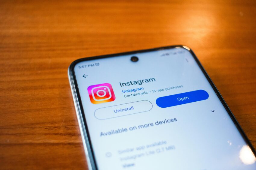 Smartphone screen displaying the Instagram app page on Google Play Store with options to uninstall or open the app, placed on a wooden surface.